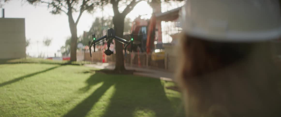 A construction worker flies his drone over the lawn