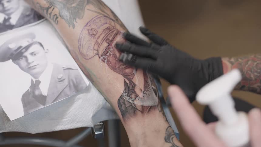 A tattoo artist is putting cream on a finished tattoo