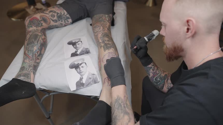 A man tattoos a portrait onto a customers leg