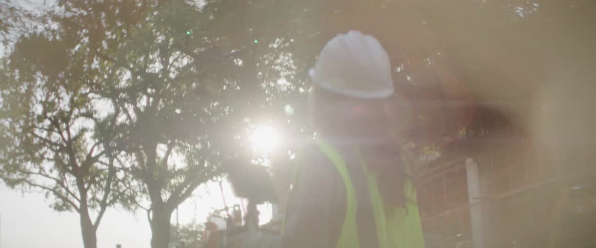 A construction worker is flying a drone on a site