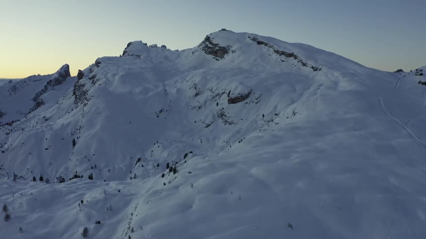 Aerial view of the snow covered slopes of a mountain range at sunset