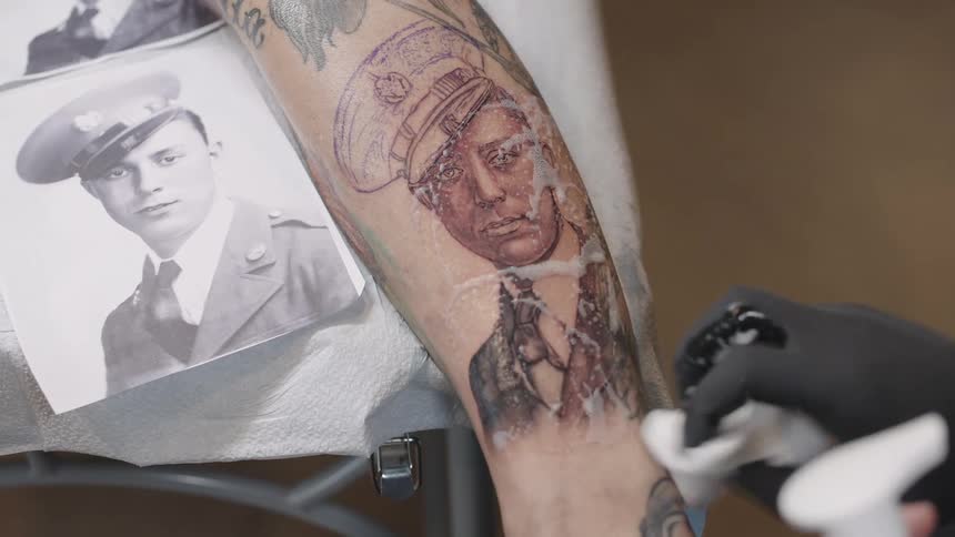 Tattoo artist cleaning a fresh tattoo on the leg of a client