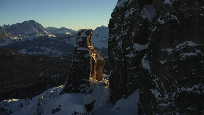 Aerial view of rock formations covered in snow in the mountains at sunset
