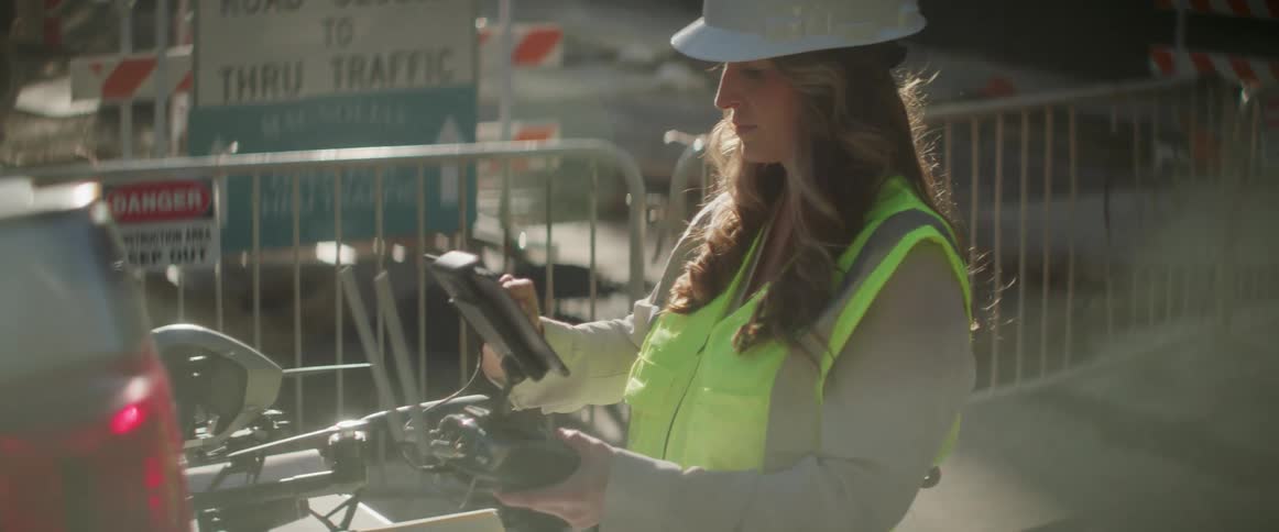 A female construction worker is working with an electronic device