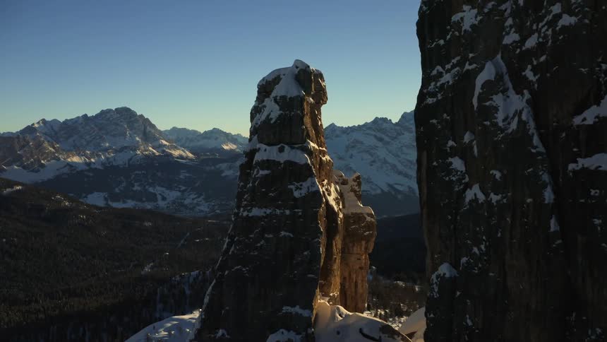 Cliffs covered in snow with a mountain range the sky and clouds in the background