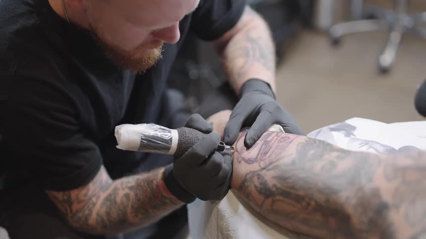 A tattoo artist is copying a picture onto somebodys arm