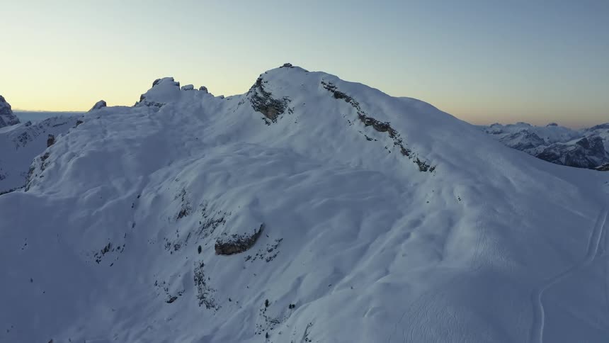 Aerial view of snowy mountain slope at dusk