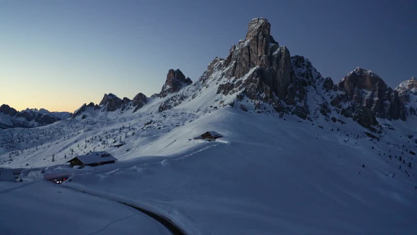 Aerial view of a cabin on the snow covered slopes near the mountain peak at sunset