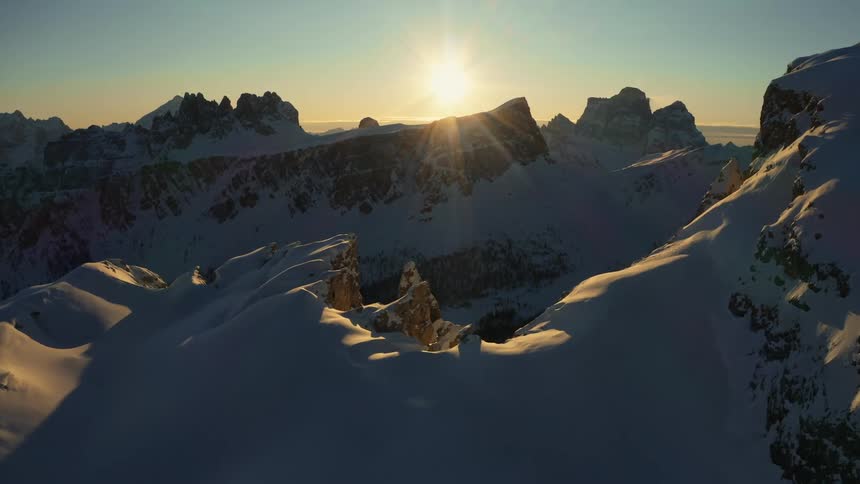 The sun is setting over a snow covered mountain range