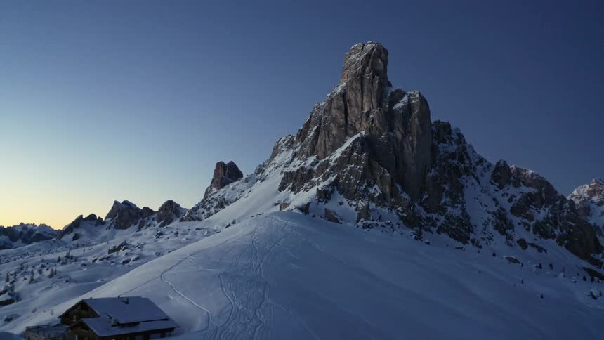 A lone building on a snowy mountainside in rocky mountains on a winter morning