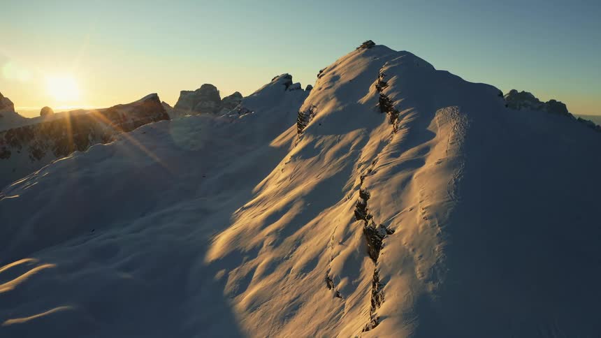 The sun is reflecting off the snow on a mountain peak