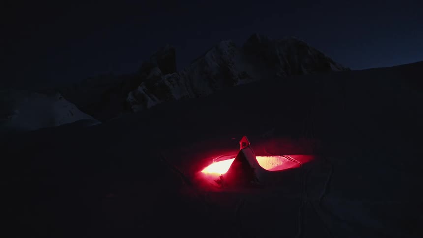 A bright light glowing in front of a building in a mountain range