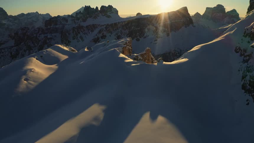 The sun is setting over snow covered mountain peaks