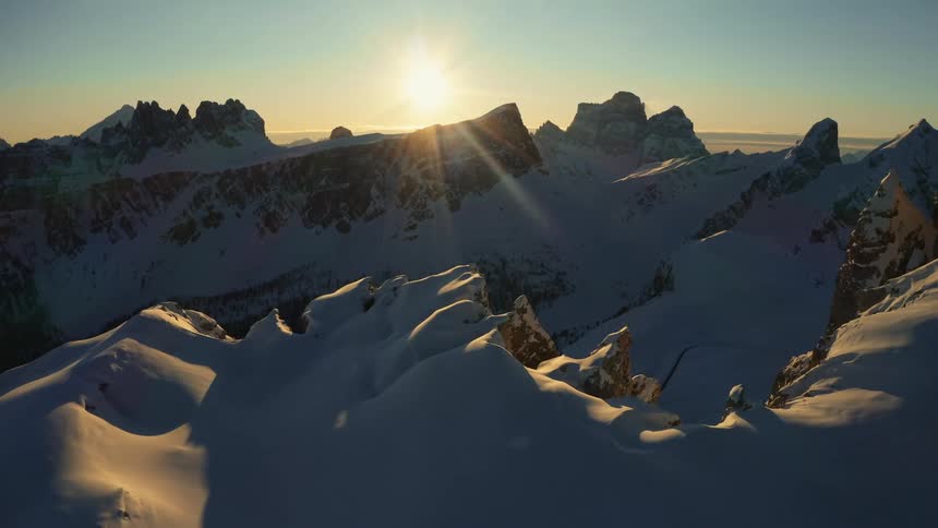 The sun is rising on the snow covered mountain range