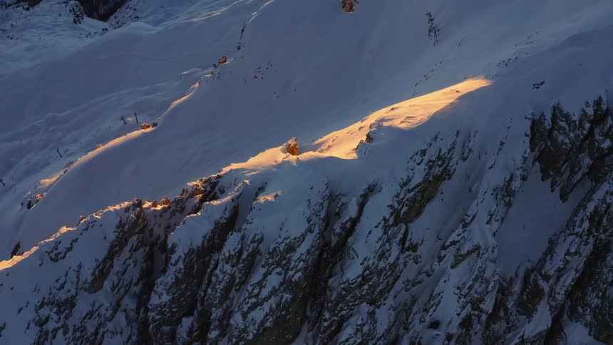 An aerial view of a snowy mountain range in the wilderness on a clear winter morning