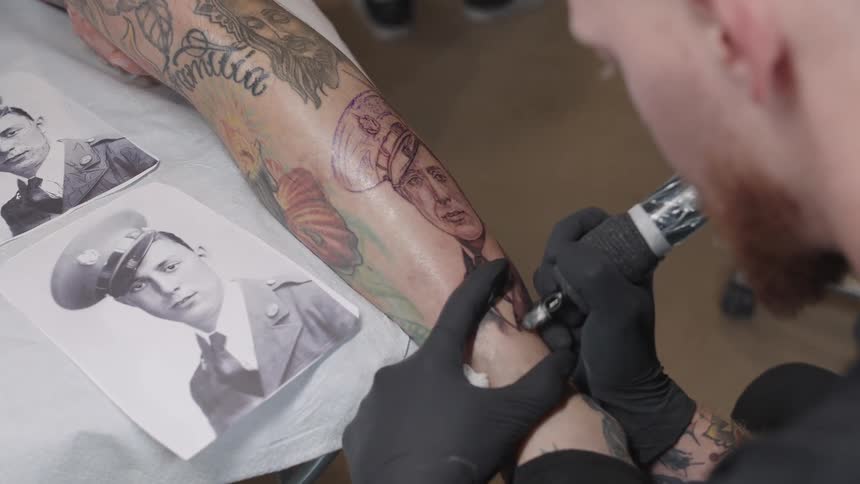 Tattoo artist reproducing and old time photograph on a clients leg