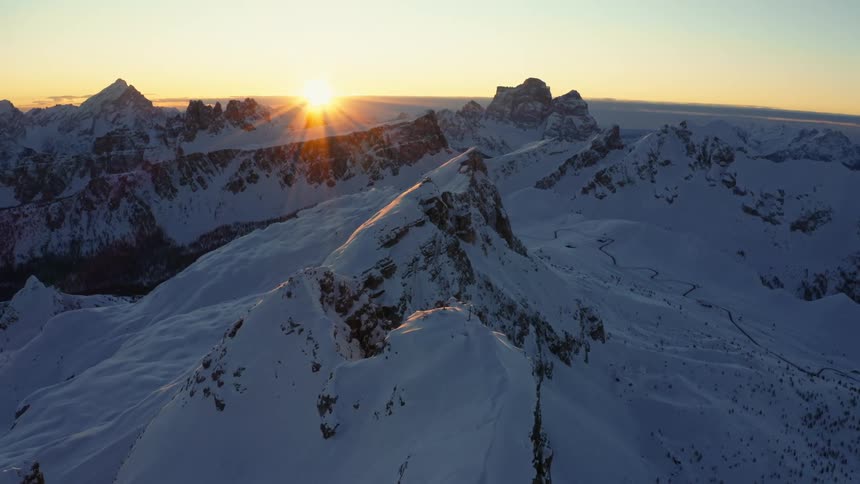 Snowy mountain peaks as the sun peaks over the horizon