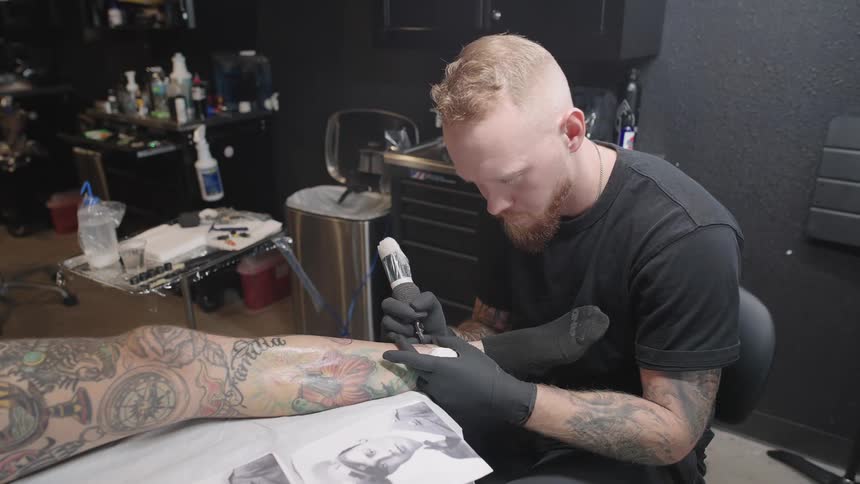 A man tattooing on another persons leg
