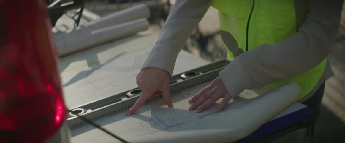 Engineer uses a level ruler to take measurements on a blueprint