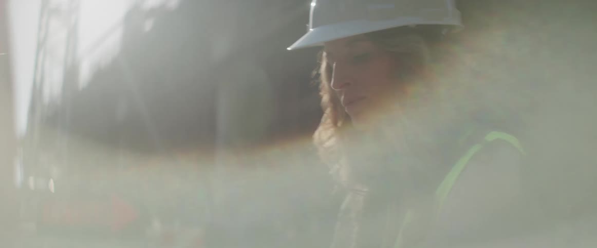 A female construction worker is outside looking at a map