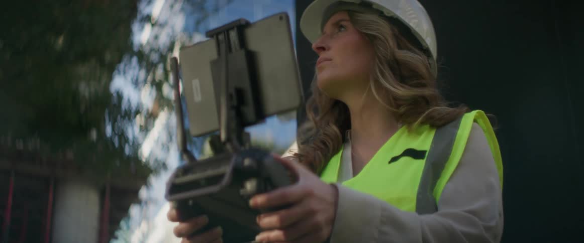 A woman is using a controller and tablet on a construction site