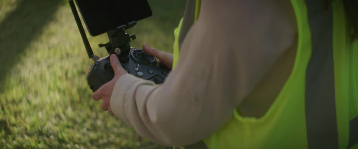 Construction worker uses a drone remote control over the lawn at morning