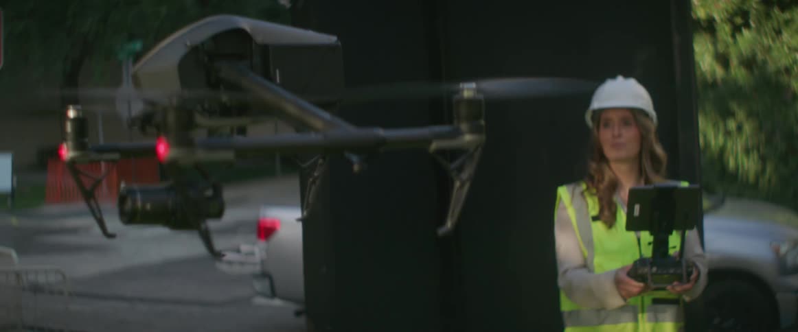 A construction workers watches as she lands a drone