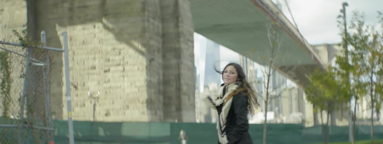 A woman walks near a bridge on a windy day
