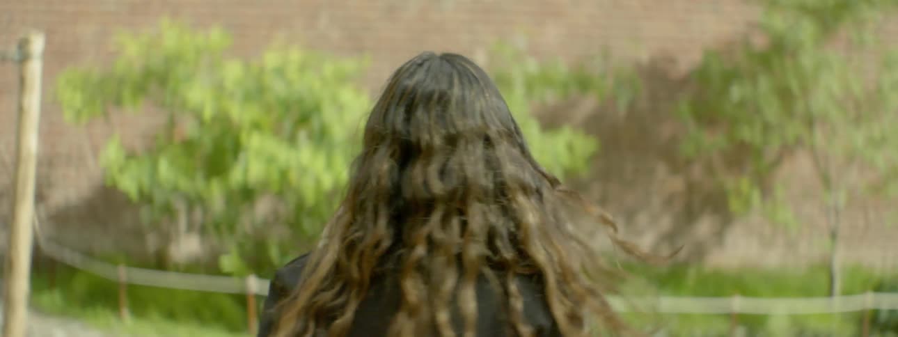A woman is walking outside before turning around smiling