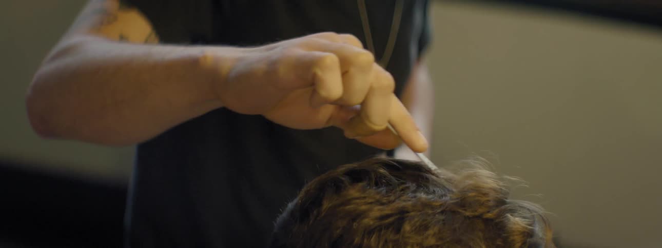 Barber trimming patron's hair with comb and scissors