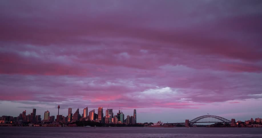 Time lapse of clouds rolling over the skyline of a coastal city at morning