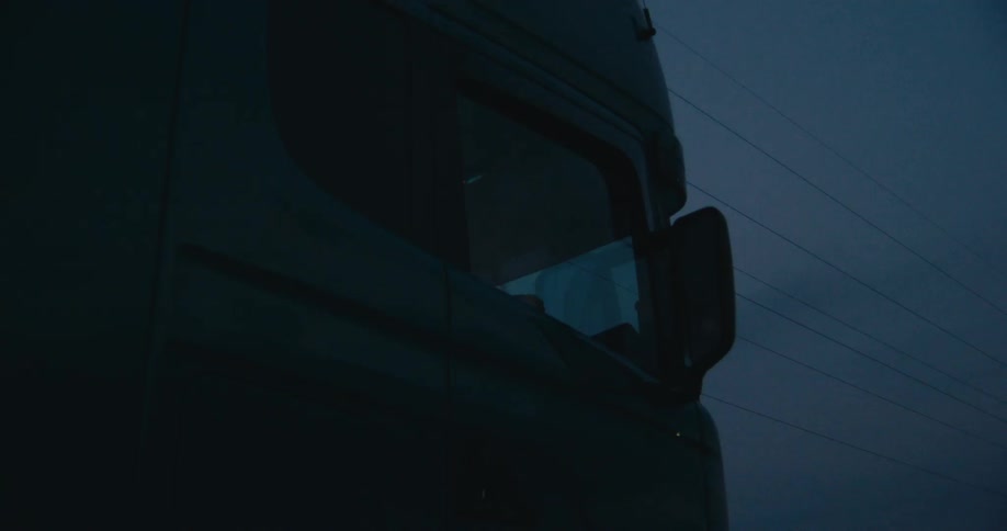 A vehicle driving with utility poles signs the sky and clouds in the background