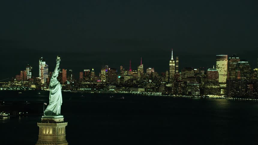 The statue of liberty is lit up at night
