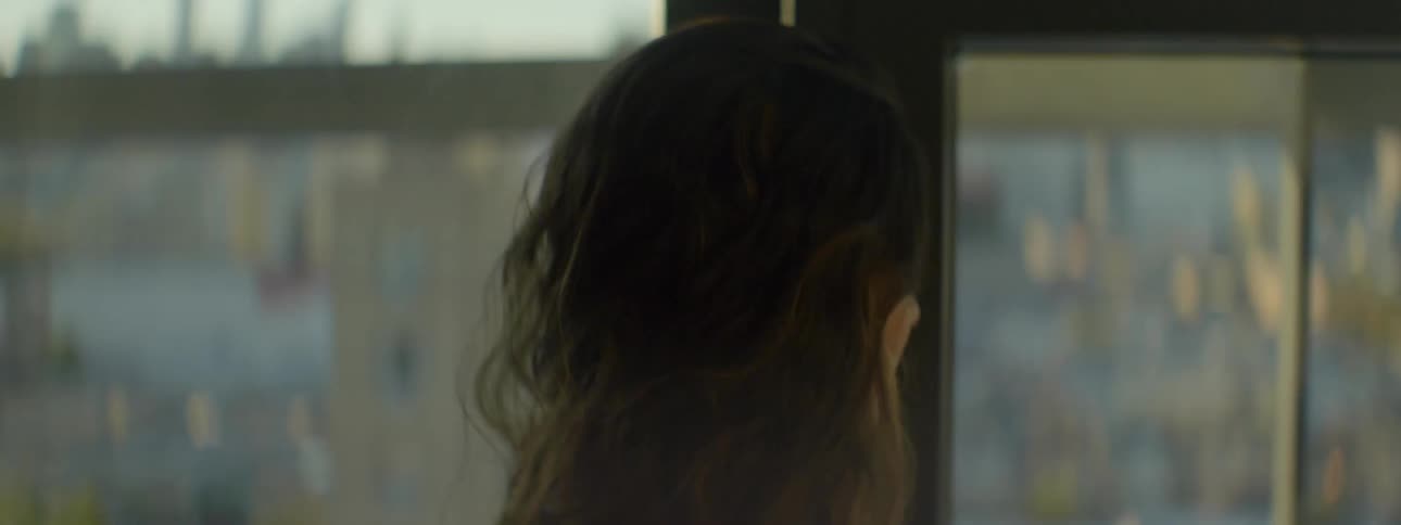 A woman is standing close to a window looking outside