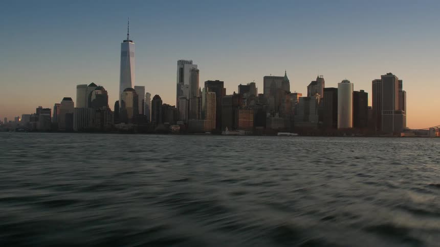 A body of water with the city skyline with buildings and skyscrapers with the sky and clouds in the background