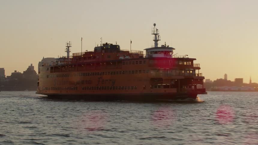 The staten island ferry is traveling across the water