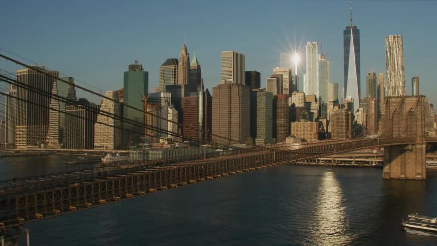 Aerial view of the brooklyn bridge in front of the new york city skyline at sunset