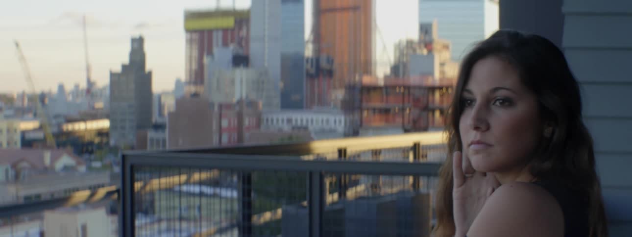 Woman standing on a balcony overlooking a large city