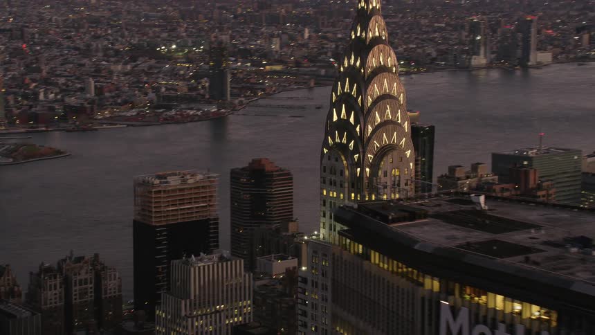A tall skyscraper near a river in a metropolis in the evening