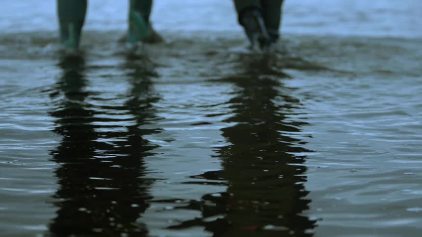 People wearing waterproof rubber boots walking on shallow water