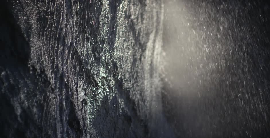 Rain pours off the rock formation