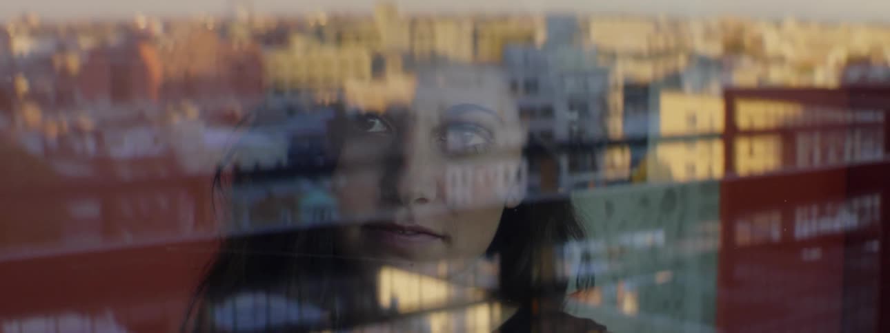 A dark haired woman looks out of the window