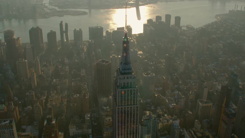 The empire state building standing tall around other buildings in new york city