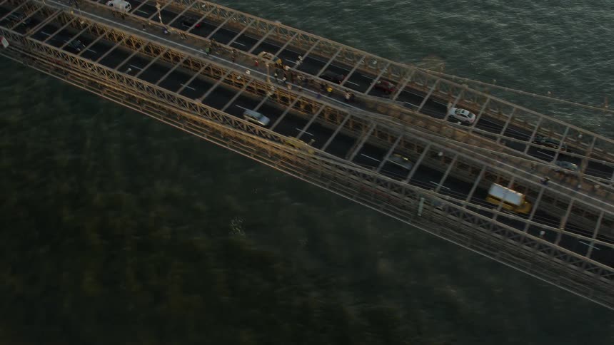 Traffic travels across a long bridge across a waterway during the day