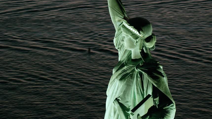 The statue of liberty with the sea buildings the sky and clouds in the background