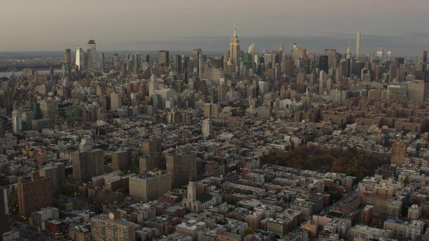 An aerial view of a city skyline with a waterway in the distance
