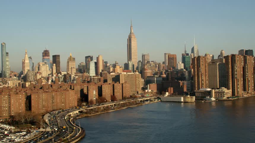 An aerial view of cars driving along the shore next to high rise office buildings in a downtown area