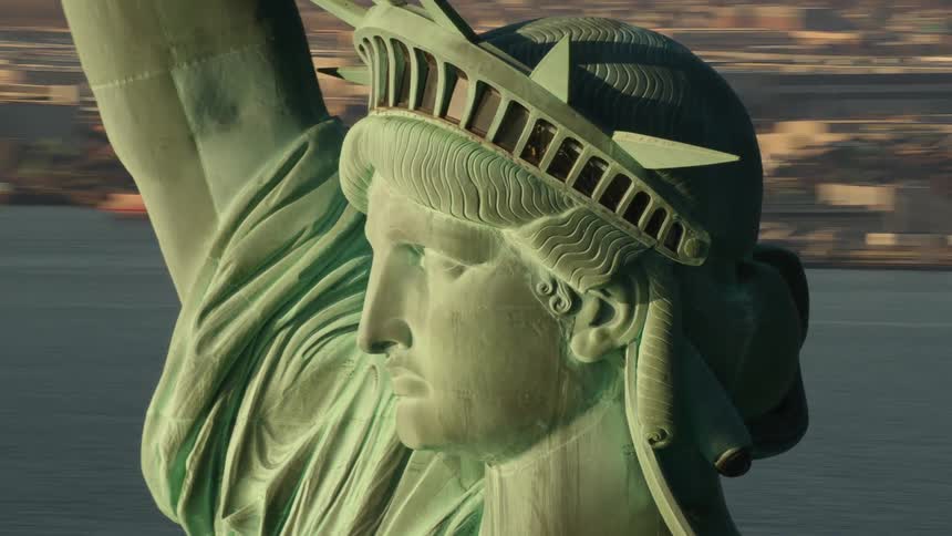 The statue of liberty is in the water by the city