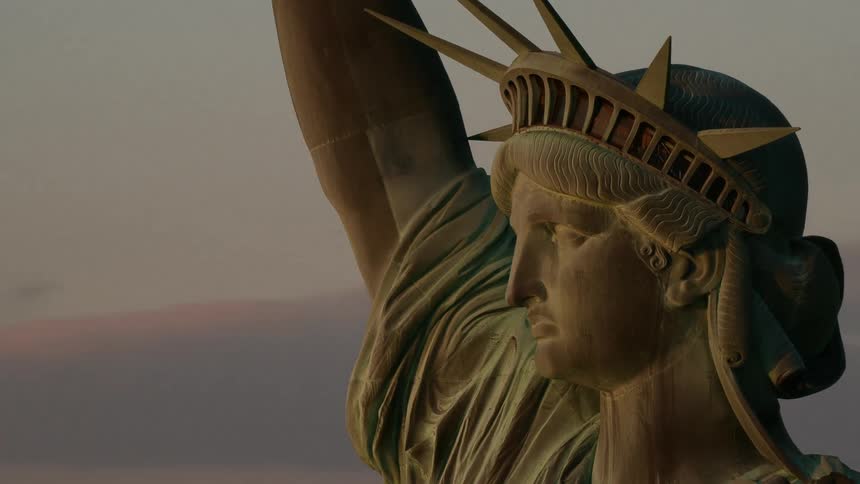 Aerial view of the statue of liberty in front of new york city at sunset