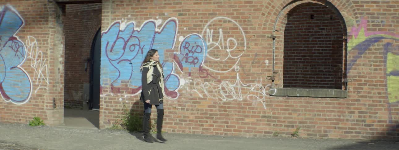 A woman exits a brick building and walks down a street